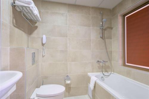 a bathroom with a toilet and a tub and a sink at Radisson Hotel Plovdiv in Plovdiv