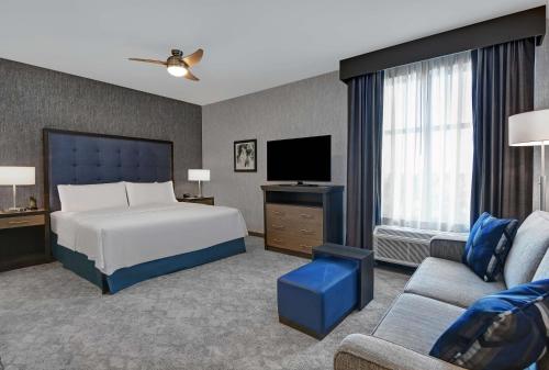Homewood Suites By Hilton Edison Woodbridge, NJ في إديسون: غرفة نوم بسرير وتلفزيون وأريكة