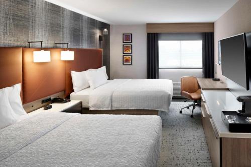 a hotel room with two beds and a desk at Hampton Inn Newark Airport in Newark