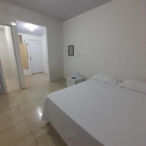 a white bedroom with a white bed and a hallway at Pousada Estelita in Itaparica Town
