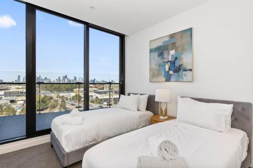 twee bedden in een kamer met een groot raam bij Breathtaking City & River Views HUGE Balcony! in Melbourne