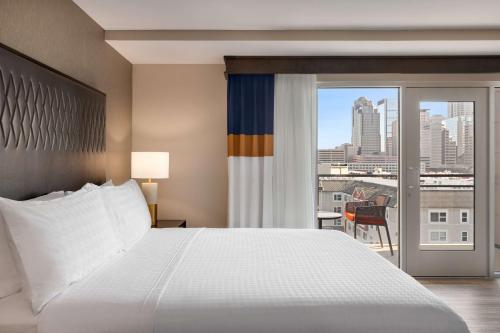 a bedroom with a bed and a view of a city at Homewood Suites by Hilton Indianapolis Downtown IUPUI in Indianapolis