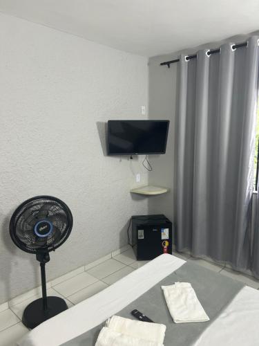 a room with a fan and a tv on the wall at Pousada Coqueiros in Cabo Frio