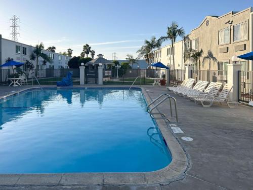 a large blue swimming pool with chairs and buildings at Studio 6 Suites Carson, CA in Carson