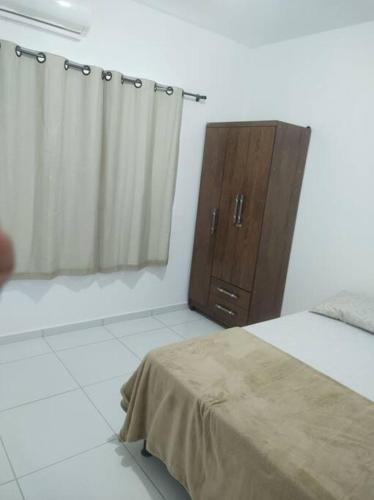 a bedroom with a bed and a wooden cabinet at Apt há 10 minutos da Praia. in São-José-do-Ribamar