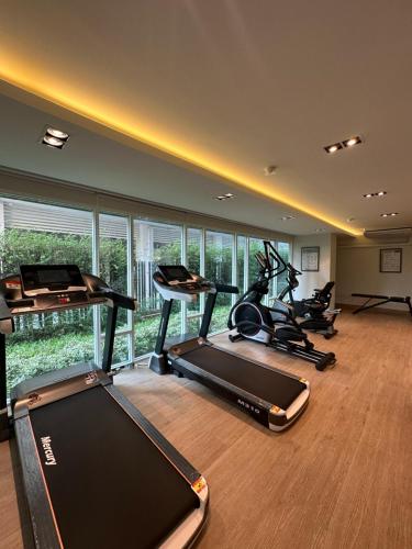 a gym with several treadmills and elliptical machines at The East Ville in Ban Hua Khao Sammuk