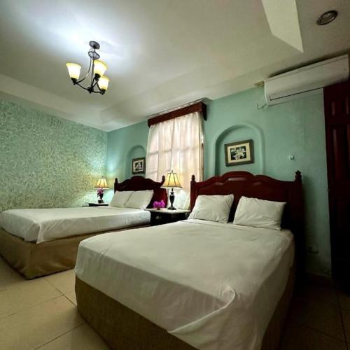two beds in a bedroom with blue walls at Hotel Aloha Managua in Managua