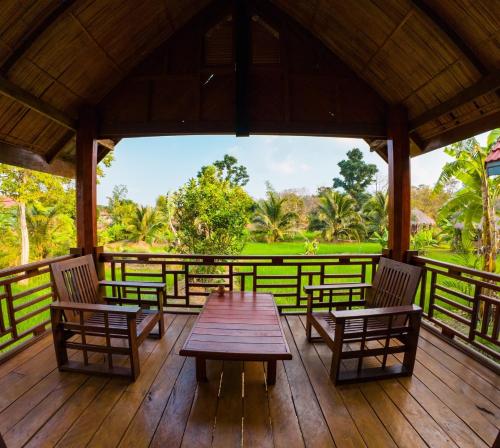 una mesa de madera y sillas en una terraza de madera en BOLAVEN GARDEN Bungalow and tent - Tad Lo, en Ban Kiangtat