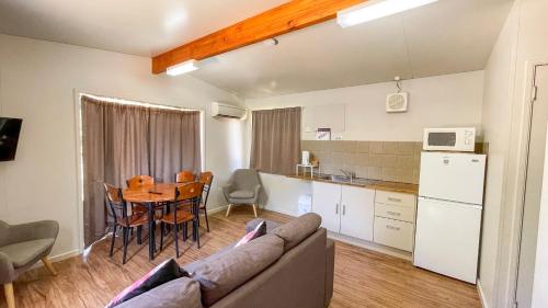 a kitchen and a living room with a couch and a table at Capricorn Holiday Park in Carnarvon