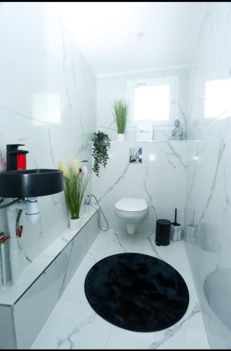 ein weißes Bad mit einem WC und einem schwarzen Teppich in der Unterkunft CasaLova in Épinay-sur-Seine