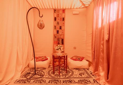 een kamer met 2 stoelen, een tafel en een lamp bij Imperial Glory Lodges in Merzouga