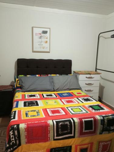 - une chambre avec un lit et une couverture colorée dans l'établissement Casa da roça, à Espera Feliz