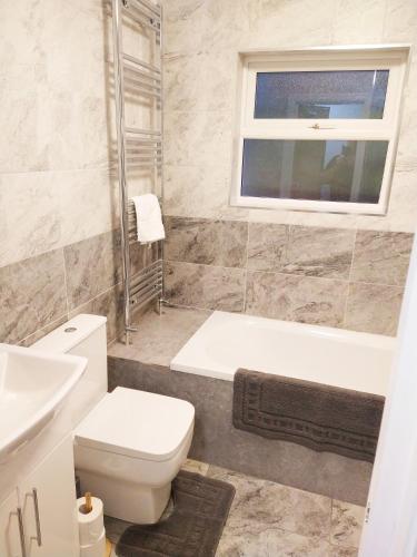 La salle de bains est pourvue de toilettes, d'une baignoire et d'un lavabo. dans l'établissement Park Lane Ground Floor Apartment - Workington Town Centre, à Workington