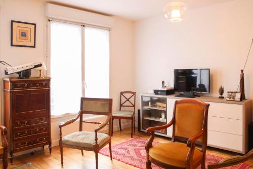 een woonkamer met 2 stoelen en een televisie bij Lovely and spacious 140 m house in Paris 12th in Parijs