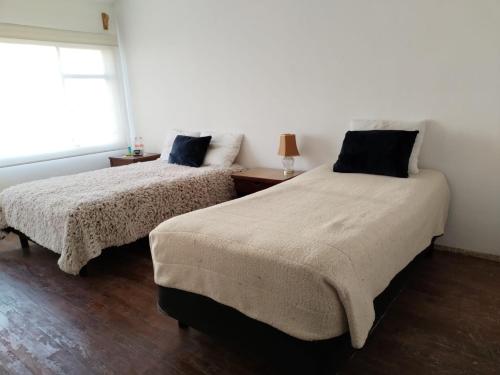 two beds in a white room with a window at La Cortesana in Mexico City