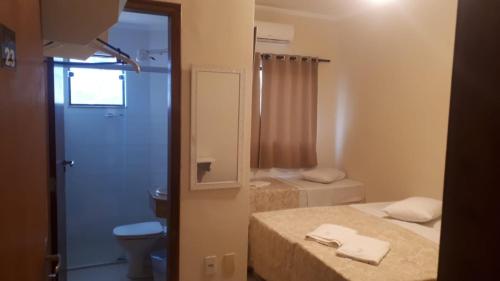 a bathroom with two beds and a toilet and a mirror at Vila Santa Hotel in Aparecida