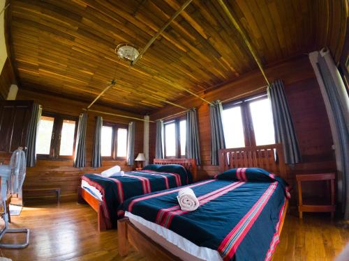 Duas camas num quarto com paredes e janelas de madeira em BOLAVEN GARDEN Bungalow and tent - Tad Lo em Ban Kiangtat