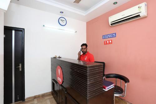 un hombre hablando en un celular en una habitación en OYO 429 Hotel Kisna Residency, en Gurgaon