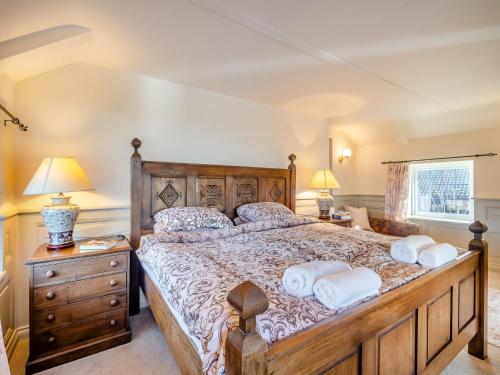 una camera da letto con un grande letto in legno con due cuscini di Ship Cottage a Reedham