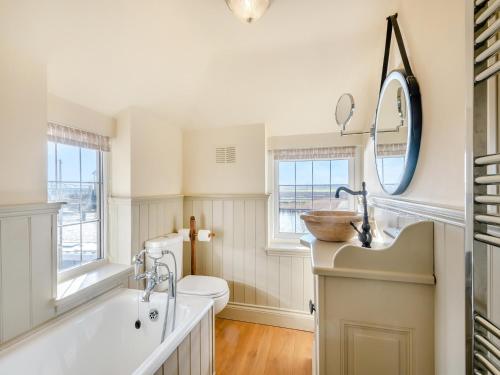a bathroom with a tub and a sink and a toilet at Ship Cottage in Reedham