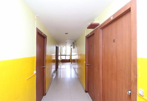 an empty hallway with wooden doors and yellow walls at OYO Hotel Maruti Lodging in Dum Dum