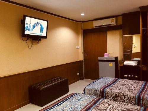 a hotel room with two beds and a tv on the wall at จินตคามโฮมเพลส/Jintakam Home Place in Udon Thani