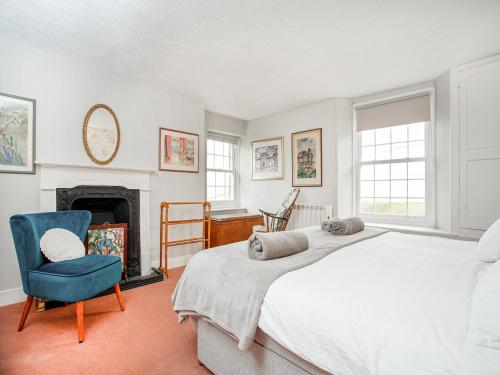 a bedroom with a bed and a chair and a fireplace at Lee House in Fowey