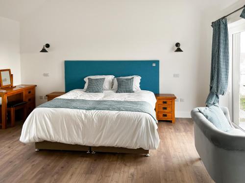 1 dormitorio con 1 cama y cabecero azul en Bayview Byre, en Knock