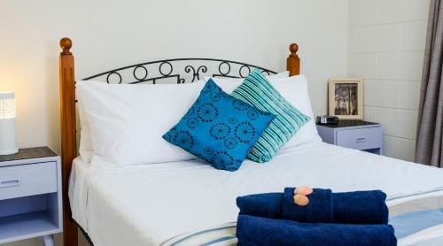 a bedroom with a white bed with blue pillows at Kurrimine Fishing Haven - Pet Friendly in Kurrimine Beach