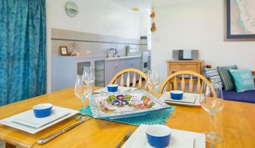 a dining room table with a plate and glasses on it at Kurrimine Fishing Haven - Pet Friendly in Kurrimine Beach