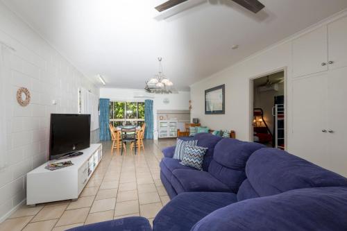 a living room with a blue couch and a tv at Kurrimine Fishing Haven - Pet Friendly in Kurrimine Beach