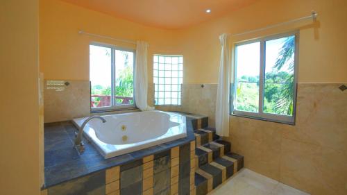 baño grande con bañera y 2 ventanas en Royal Palms Estate en Christiansted