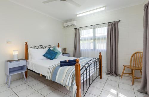 a bedroom with a bed and a chair and a window at Kurrimine Fishing Haven - Pet Friendly in Kurrimine Beach
