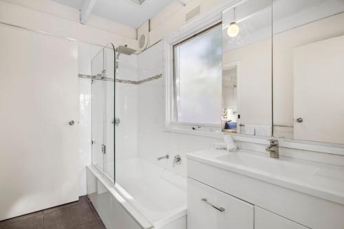 a white bathroom with a shower and a sink at Torquay Boulevard Beach House in Torquay