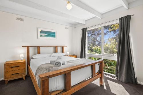 a bedroom with a bed and a large window at Torquay Boulevard Beach House in Torquay