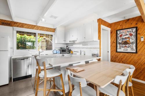 a kitchen with a wooden table and white cabinets at Torquay Boulevard Beach House in Torquay