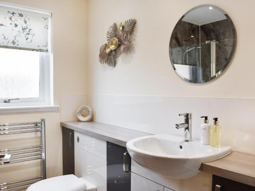 een badkamer met een wastafel en een spiegel bij Rycon in Turriff