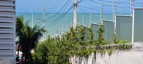 una valla con plantas y el océano en el fondo en Ponta Negra Beach 234-Natal-RN-Cantinho Potiguar, en Natal