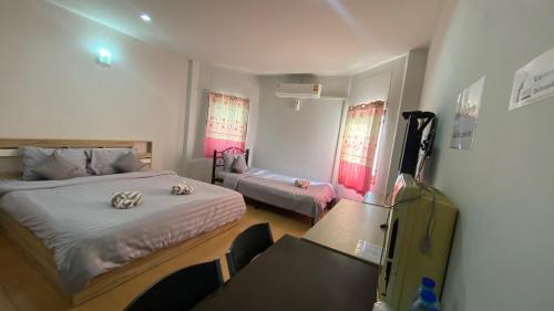 a bedroom with a bed and a table and chairs at Alongkorn hotel by SB in Samut Songkhram