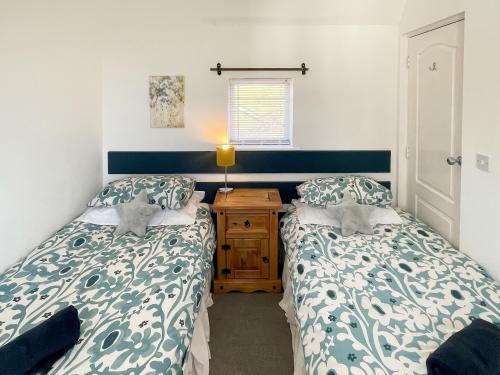 a bedroom with two beds and a wooden night stand at Anglers Rest in Stoke Gabriel