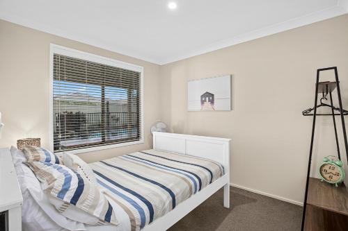 a white bedroom with a bed and a window at Emerald Hub 1 and 2 in Emerald Beach