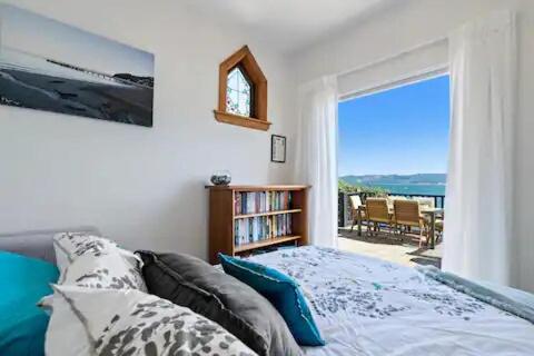 a bedroom with a bed and a book shelf and a window at Seaglass Cottage in Lower Hutt