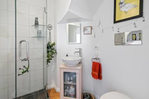 a bathroom with a sink and a glass shower at Seaglass Cottage in Lower Hutt
