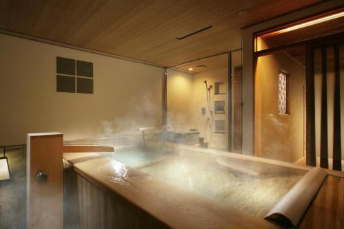 a bath tub filled with steam in a bathroom at Gora Kadan in Hakone