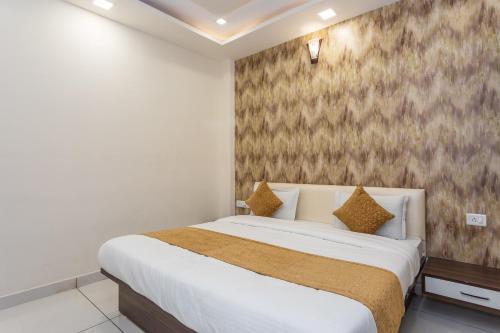 ein Schlafzimmer mit einem weißen Bett mit braunen Akzenten in der Unterkunft OYO Flagship Hotel Shri Vilas in Bhopal