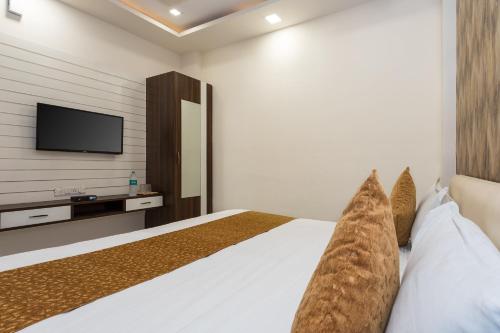 a bedroom with a bed with a tv on the wall at OYO Flagship Hotel Shri Vilas in Bhopal