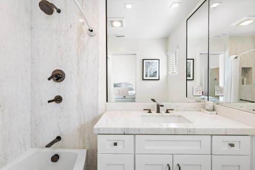La salle de bains blanche est pourvue d'un lavabo et d'un miroir. dans l'établissement Amazing New & Water Vu/Balboa Peninsula! EV charge, à Newport Beach