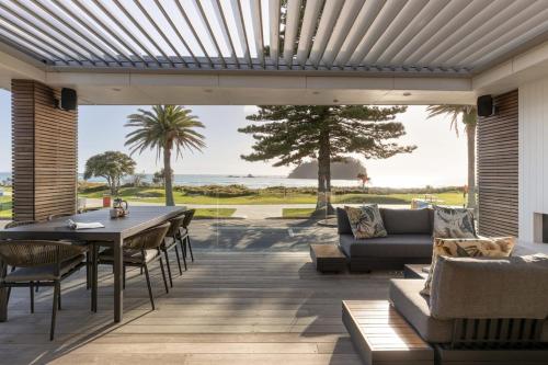 a patio with a table and chairs and a view of the ocean at 36 Marine - Unparalleled beachfront luxury in Mount Maunganui