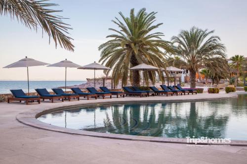 a pool with chairs and umbrellas on the beach at Playa de La Paz 3 BR Condo Access to Beach club in La Paz