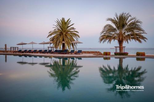 a pool at a resort with palm trees and chairs at Playa de La Paz 3 BR Condo Access to Beach club in La Paz